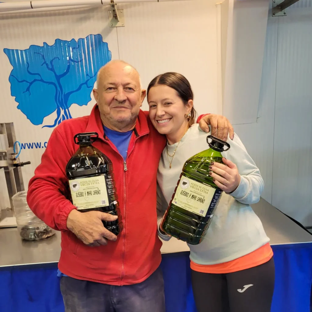 imagen de un padre y su hija satisfechos y felices enseñando su aceite embotellado - Campos de Jaén